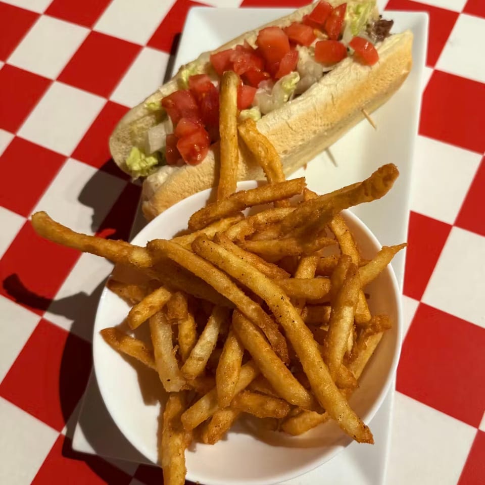 High's Restaurant's cheesesteak sub with diced tomatoes and lettuce, served with a side of fries.
